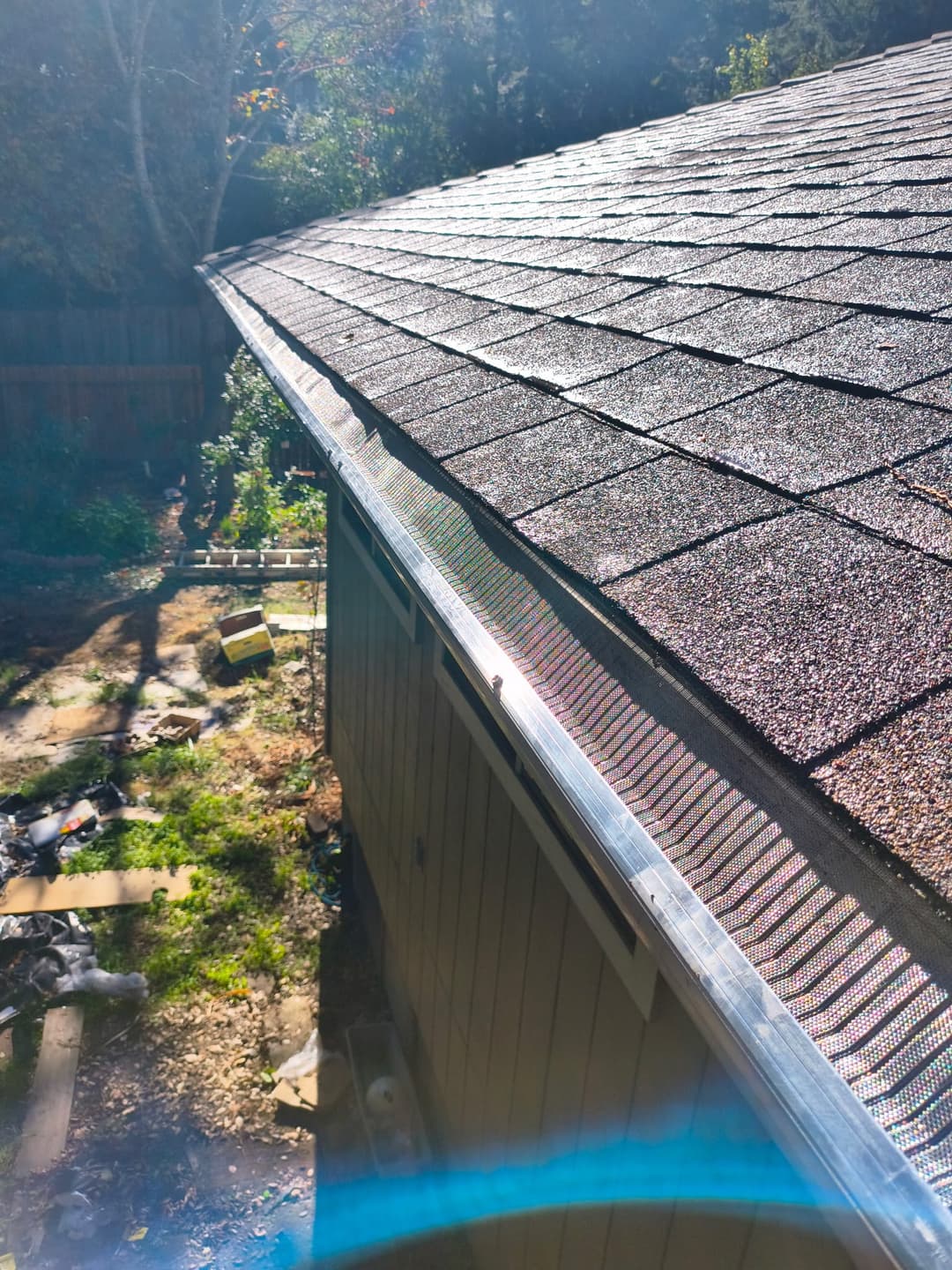 Close-up view of a house roof with newly installed metal gutter guards in bright sunlight